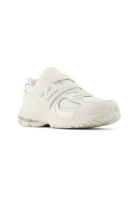 White athletic shoe with a textured upper, adjustable strap, and a cushioned sole. Features mesh accents and a rubber tread pattern.