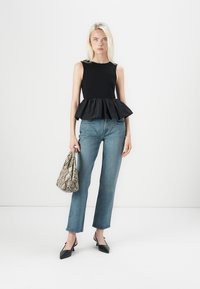 Musthave mustrõngaga must seinaga peplum top, helesinised sirged teksad ja mustad terava ninaga kontsad. Hoides nahkhiire mustriga käekotti.