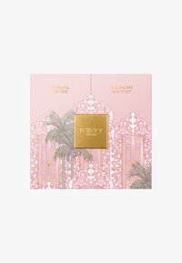 Boîte de kit de beauté décorative rose avec fermoir doré, motifs ornés, illustrations de palmiers, et texte "Threads of Time" et "Oud Escape Beauty Kit".