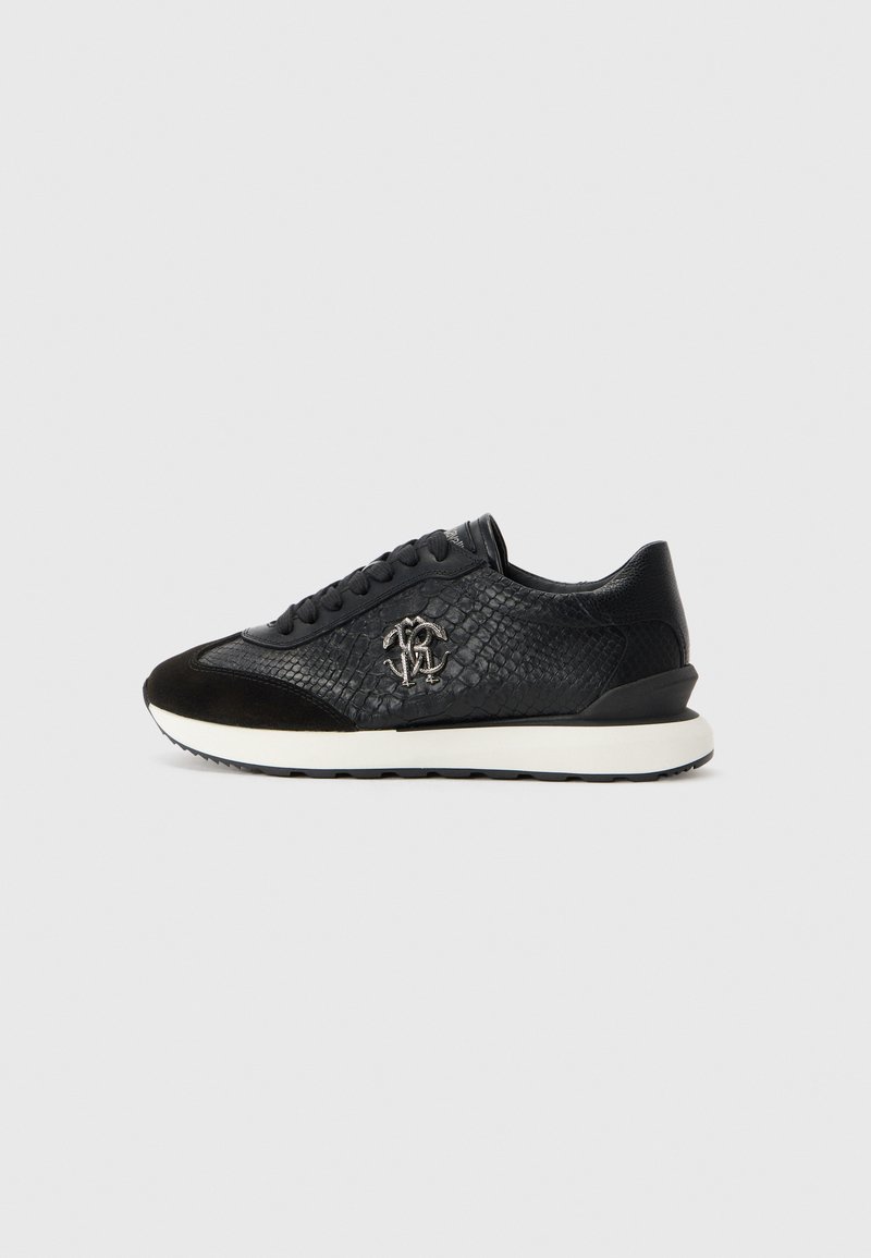 Black sneaker with textured snakeskin pattern, suede toe, lace-up design, white sole, and metallic logo on the side.