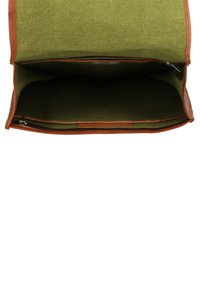 Borsa di tela con un interno verde e dettagli in pelle marrone. Presenta un ampio scomparto aperto e una tasca con zipper.