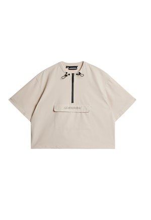 Chemise beige à manches courtes avec un col montant, fermeture éclair demi-longue à l'avant, cordon de serrage ajustable et poche poitrine avec un logo en relief.