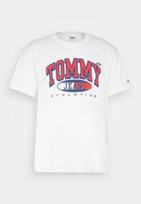 Tricou alb din bumbac, cu un imprimeu grafic îndrăzneț în roșu și albastru "TOMMY JEANS ATHLETICS" pe față. Mâneci scurte și decolteu rotund.