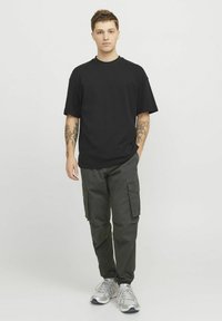 Sort bomulds T-shirt med korte ærmer, parret med mørkegrønne cargo-bukser med flere lommer og grå løbesko.