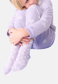 Pigiama viola con una texture morbida; la parte superiore presenta un motivo a cuori, mentre i pantaloni hanno piccoli pois bianchi. I calzini sono dello stesso colore dei pantaloni.