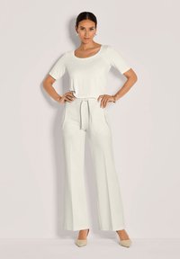 Hellgraues Zweiteiler-Outfit mit einem Oberteil mit Rundhalsausschnitt und weit geschnittenen Hosen mit Fronttaschen. Glatte Textur, lässige Passform und mit Kordelzugbund.