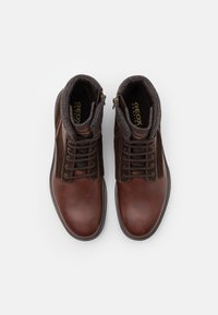 Paire de bottines montantes à lacets en cuir marron et daim avec col rembourré et fermetures éclair latérales, vues de dessus sur fond blanc.