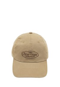 Căciulă de baseball bej cu margine curbată, având o etichetă brodată maro pe care scrie "New York World's City 1981." Fabrică din bumbac moale.