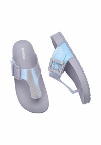 Sandali blu traslucidi con una cinghia decorata, soletta grigia e una fibbia regolabile. Suola piatta con grip testurizzato per stabilità.