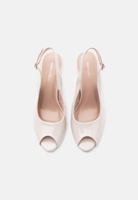 Paire de talons slingback nus en cuir verni avec bouts ouverts, brides à la cheville et marquage "ANNA FIELD" à l'intérieur.