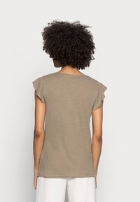 T-shirt beige con maniche corte e vestibilità rilassata, caratterizzato da maniche arricciate e scollatura tonda, realizzato in tessuto leggero e morbido.