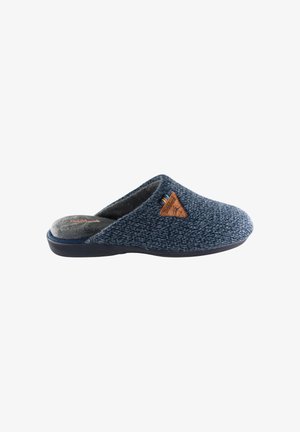 Zapatilla de punto azul con un suave forro interior, punta redondeada y un patrón texturizado. Presenta un emblema de cuero marrón en el costado.