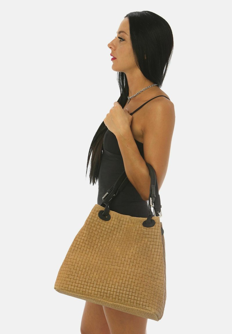 Bruine gevlochten handtas met een gestructureerd oppervlak, zwarte handvatten en metalen hardware. Gemiddelde grootte, rechthoekige vorm, opvallende stikseldetails.