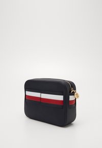 Marine blauwe leren tas met een rechthoekige vorm, voorzien van een horizontale driekleurige streep in rood, wit en blauw, en een gouden ritssluiting.