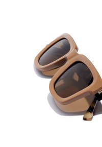 Ochelari de soare oversized, de culoare maro, cu o ramă din plastic netedă și lentile întunecate, având un model de țestoasă pe accentele sprâncenei.