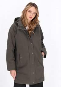 Mørkegrøn hættejakke med lynlås foran og trykknaplukninger, store side lommer og en afslappet pasform. Stoffet ser glat og holdbart ud.