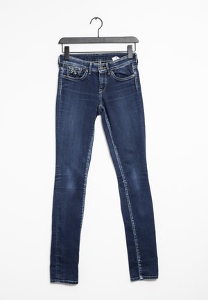 Smal jeans i mörkblå denim med lätt slitning, har fem fickor och dragkedja, hängande på en svart plastgalge.