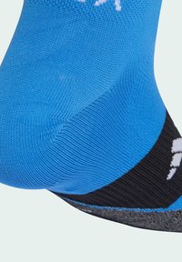 Calcetín deportivo azul con una textura acanalada, puño en negro y gris, y detalles de logo en blanco. Diseño ajustado para comodidad y soporte.