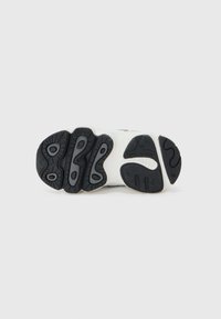 Black and white sneaker sole featuring a textured black rubber with unique tread patterns and cushioning areas for support.
