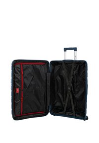 Maleta rígida en azul marino con diseño expandible. El interior presenta forro negro, bolsillo de malla con cremallera roja y correas elásticas.