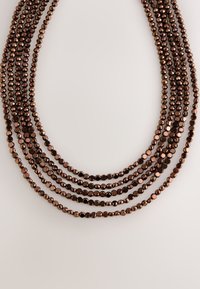 Multi-strand necklace featuring round, reflective beads in dark brown hues, arranged in graduated lengths. Smooth texture with consistent shape.