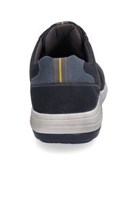 Sneaker in suede nero con accenti grigi, un tallone posteriore striato e una suola testurizzata. Presenta un collare imbottito e cuciture rinforzate.
