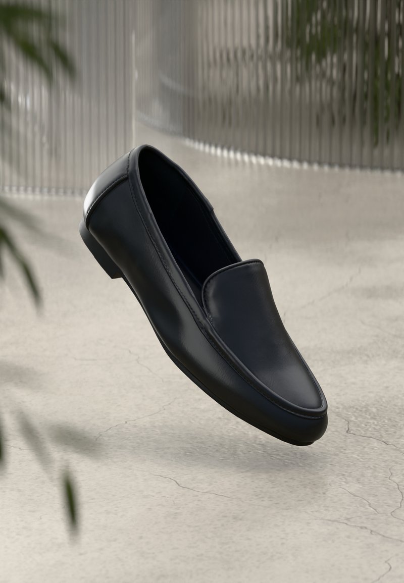 Black leather loafers with a smooth texture, pointed toe design, and minimal stitching. Features a flat, rubber sole for comfort.