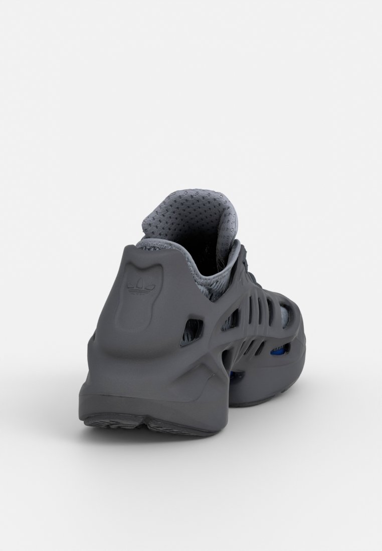 Zapatilla deportiva gris con una parte superior texturizada, orificios de ventilación, un collar acolchado y una suela de goma con un detalle azul en contraste.