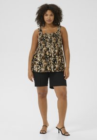 Top en imprimé léopard marron et noir avec bodice froncé, bretelles larges, associé à un short noir. Tissu doux et coupe décontractée.