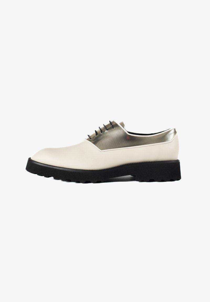 Chaussure en cuir blanc avec finition brillante, dotée d'un panneau transparent strié, semelle noire et lacets. Forme de bout arrondi.