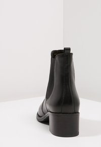 Zwarte leren Chelsea-laars met een ronde neus, elastische zijpanelen en een stevige blokhak. Glad oppervlak en strak design.