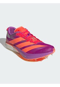 Purple and pink athletic shoe with a textured upper, striped design, and a contrasting orange toe cap; features spike plate and rubber outsole.