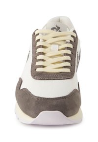 White sneaker with gray suede accents, lace-up design, textured materials, cushioned sole, and logo detail on the side.