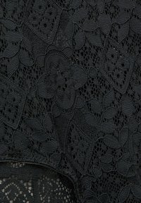 Svart spets tyg med intrikata blommönster och texturer, med öppna vävda områden och solida partier, vilket skapar en lager-på-lager effekt.