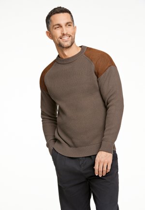 Brown ribbed sweater with brown suede shoulder accents. Features a crew neckline and long sleeves. Worn with dark pants.