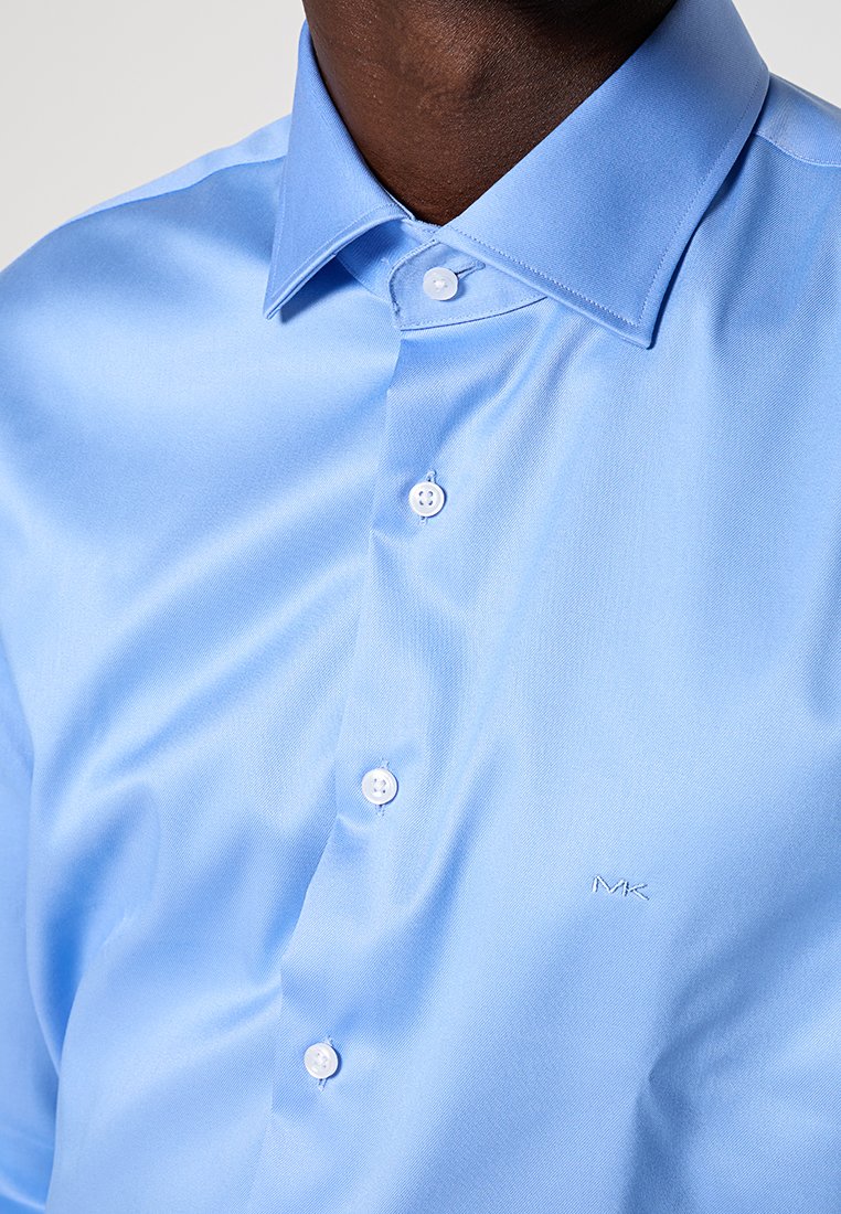 Hellblauses Kurzarmhemd aus glattem Stoff, mit klassischem Kragen und weißen Knöpfen, sowie einem dezenten, auf der Brust gestickten Logo.