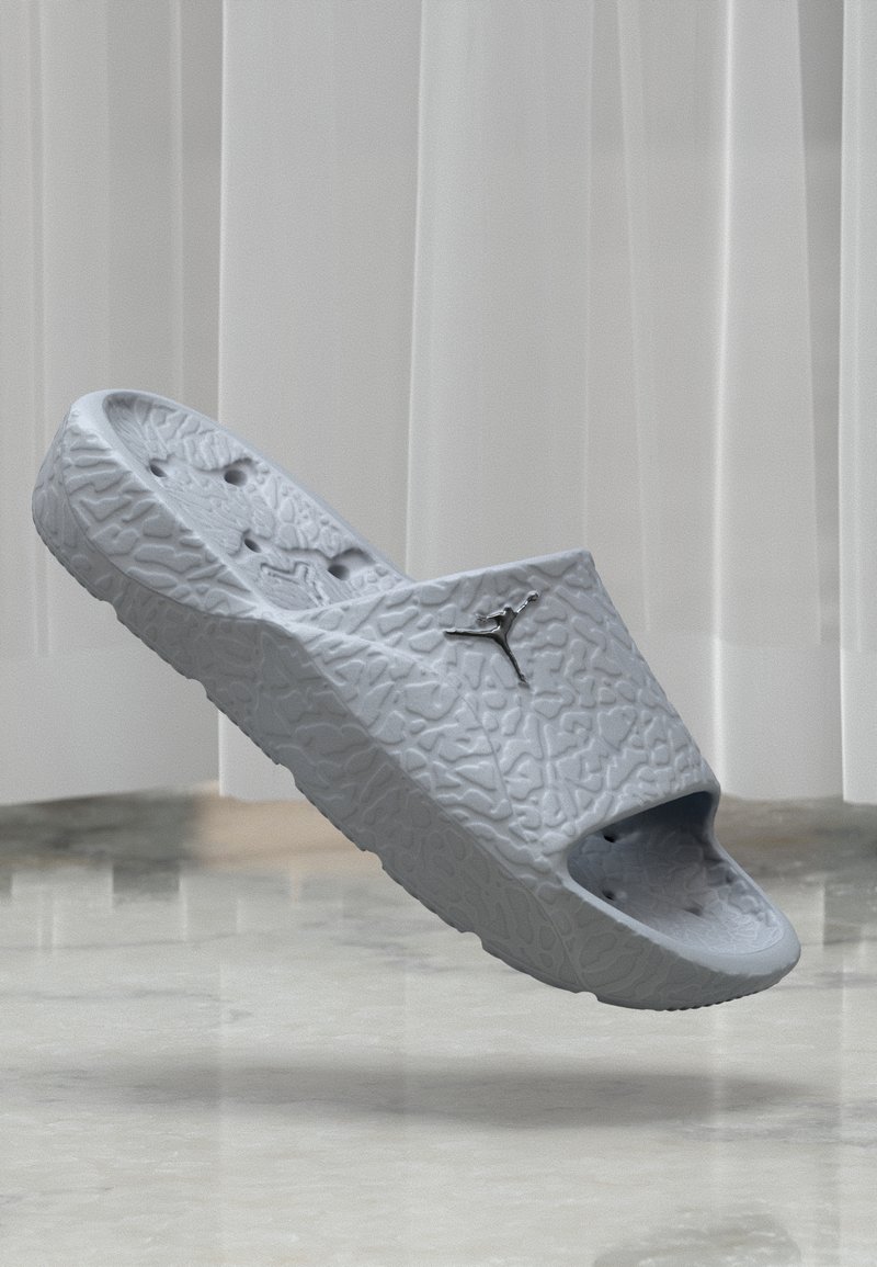 Sivi papučasti sandala izrađeni od teksturiranog materijala, s širokim otvorom i rupama za ventilaciju, s malim logotipom sa strane.
