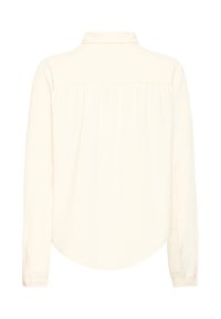 Košeľa s dlhým rukávom v off-white látke, s vystuženým golierom, manžetami na gombíky a zakriveným lemom so subtílnymi skladačkami na chrbte.