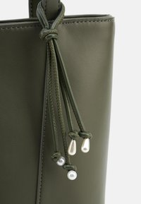 Olive green leather handbag featuring braided drawstrings with pearl accents. Smooth texture and clean design with contrasting stitching.