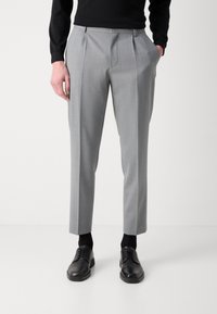 Gray pleated trousers with a smooth texture, featuring a tailored fit and side pockets, paired with black lace-up shoes and black socks.