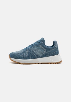 Denim sneaker in blue with textured fabric, white rubber sole, and lace-up design. Features decorative stitching and a sturdy heel counter.