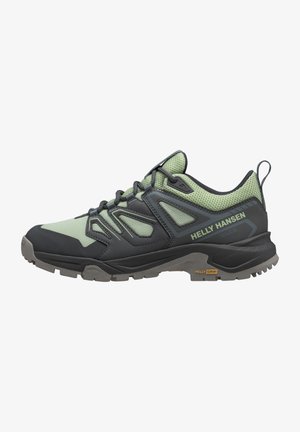 Zapatos de senderismo deportivos en verde oscuro y negro con parte superior de malla y suela de goma. Presentan un talón acolchado y una destacada marca "Helly Grip".