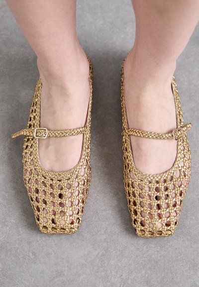 Zapatos cuadrados de punta abierta tejidos en oro con un diseño texturizado. Cuentan con una correa estrecha con una hebilla rectangular para ajustar.