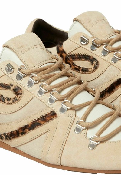 Sneaker in suede beige con lacci beige, occhielli argentati e dettagli in faux fur marrone sui lati e sulla linguetta.