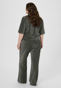 Grau schimmerndes Lounge-Set mit einem kurzärmeligen Oberteil und ausgestellten Hosen, das eine glatte Textur und einen lockeren Schnitt aufweist und subtil glitzert.