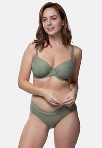 Svetlozeleni bikini set, ki vključuje strukturirano modrček z šivi in nastavljivimi naramnicami, v kombinaciji s bikini dnom z nizkim pasom. Gladka tekstura.