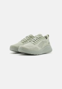 Zapatillas deportivas de color verde claro con parte superior de malla, diseño texturizado y suela acolchada. Incluye cordones y una lengüeta en el talón para facilitar su uso.