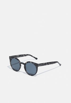 Lunettes de soleil rondes en écaille de tortue noire avec des verres bleu foncé, des branches fines et un texte de marque subtil sur la branche.