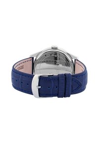 Klocka i rostfritt stål med blått läderarmband i krokodilsmönster, silverfärgad spänne och ett öppet baksidan som visar urverket.