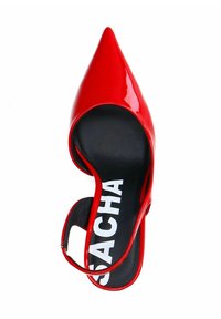 Chaussure à talon en cuir verni rouge avec un bout pointu et un dos ouvert, présentant une semelle intérieure noire avec une marque blanche. Texture lisse et design élégant.